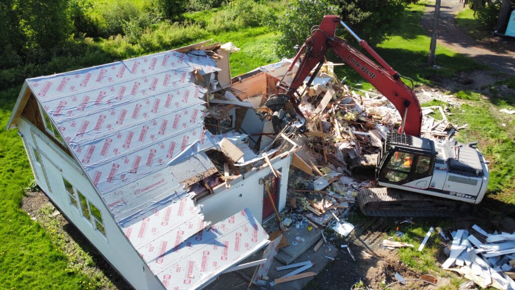 Excavator tearing down a 1933 farm house due to mold from water damage